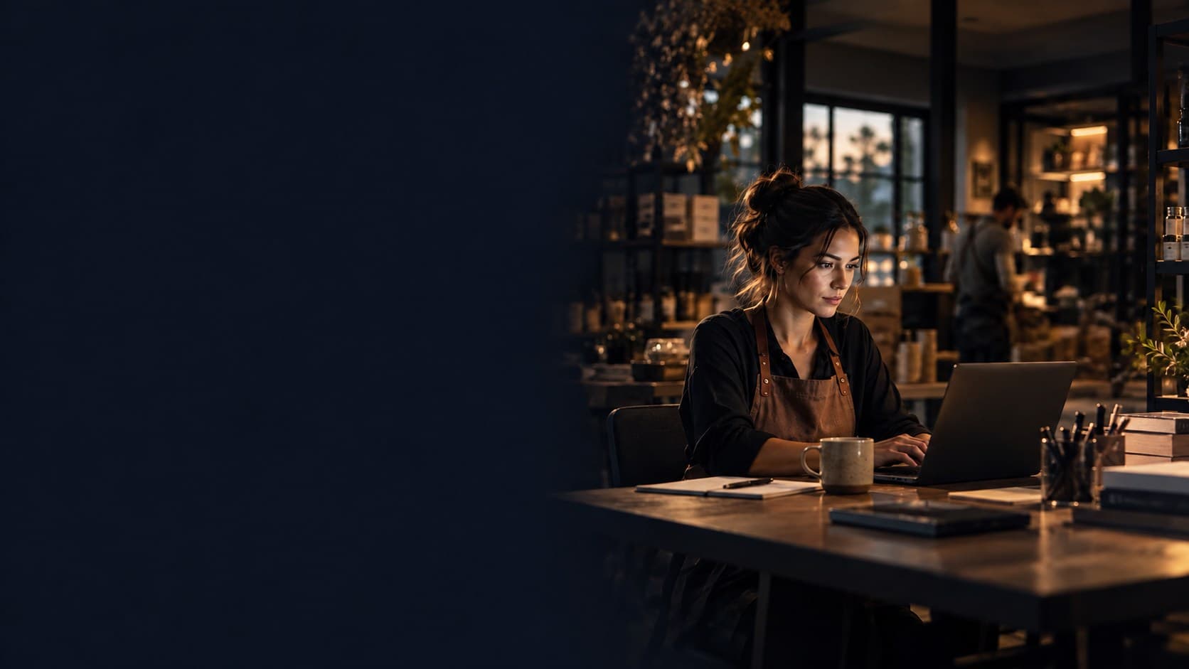 Small-business owner working at a laptop in a warmly lit studio.